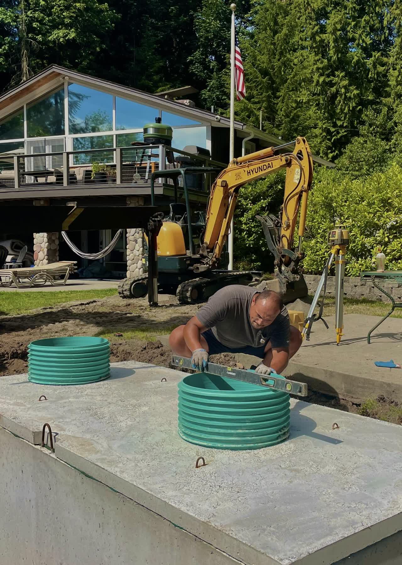 A worker checking the level of a riser on a new septic tank at a lakeside home.